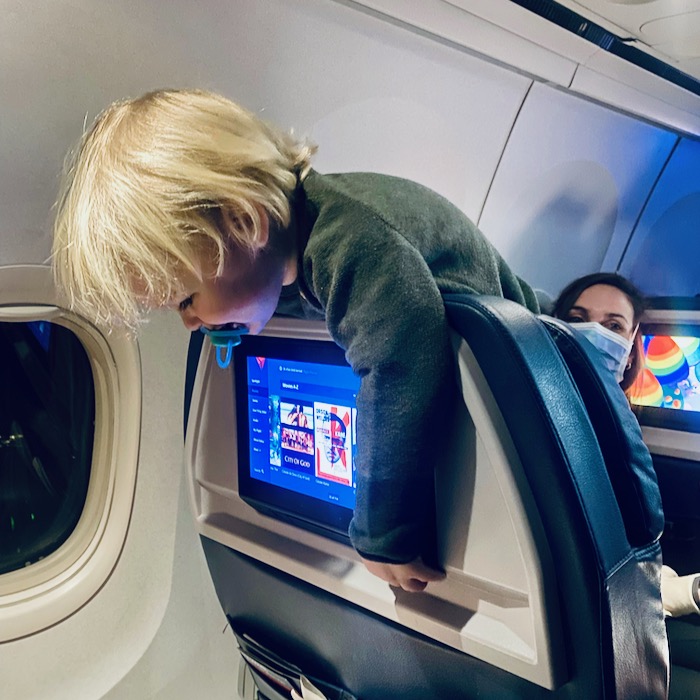 Toddler hanging over plane seat back