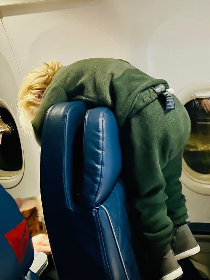 Toddler climbing over plane seat