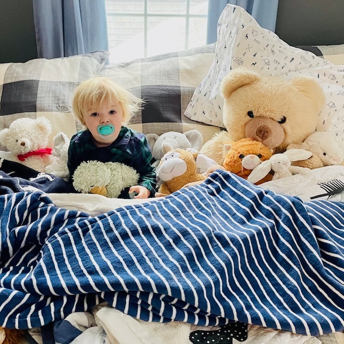 Toddler in bed with stuffed animals